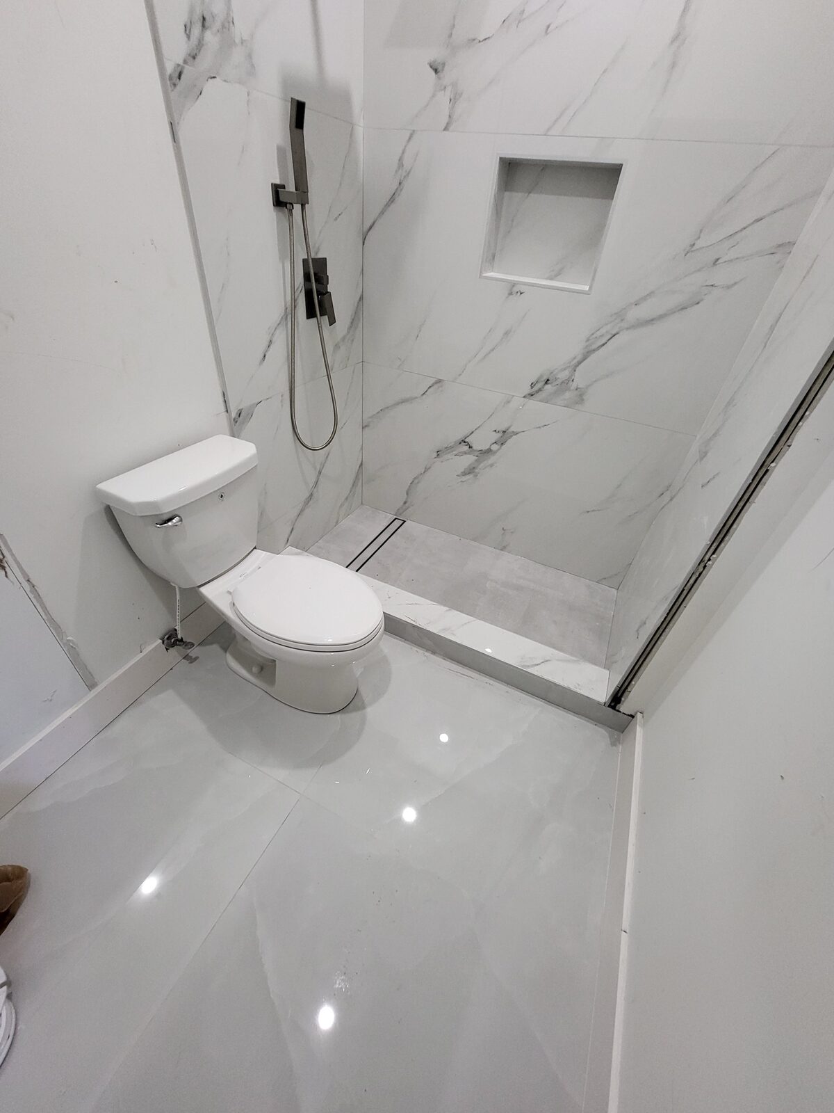 Completed bathroom with marble tile, open shower, and modern fixtures