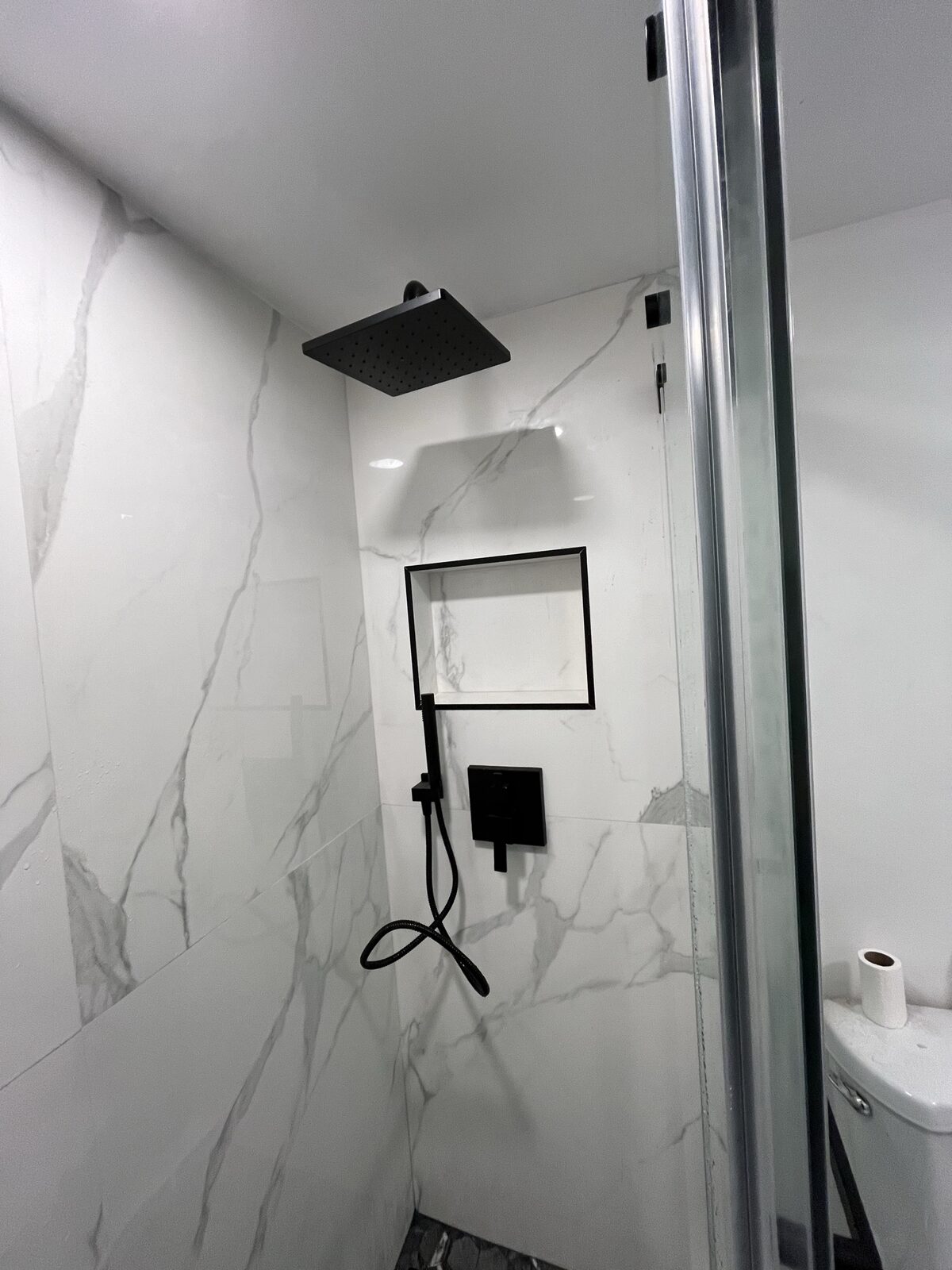 Completed bathroom remodel with black fixtures and marble tile, South Florida