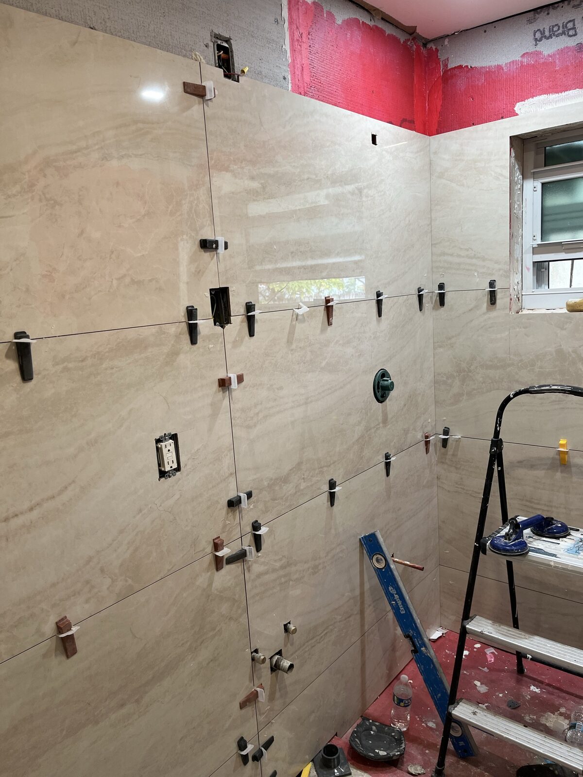 Bathroom tile in-progress showing precision large-format wall tile installation