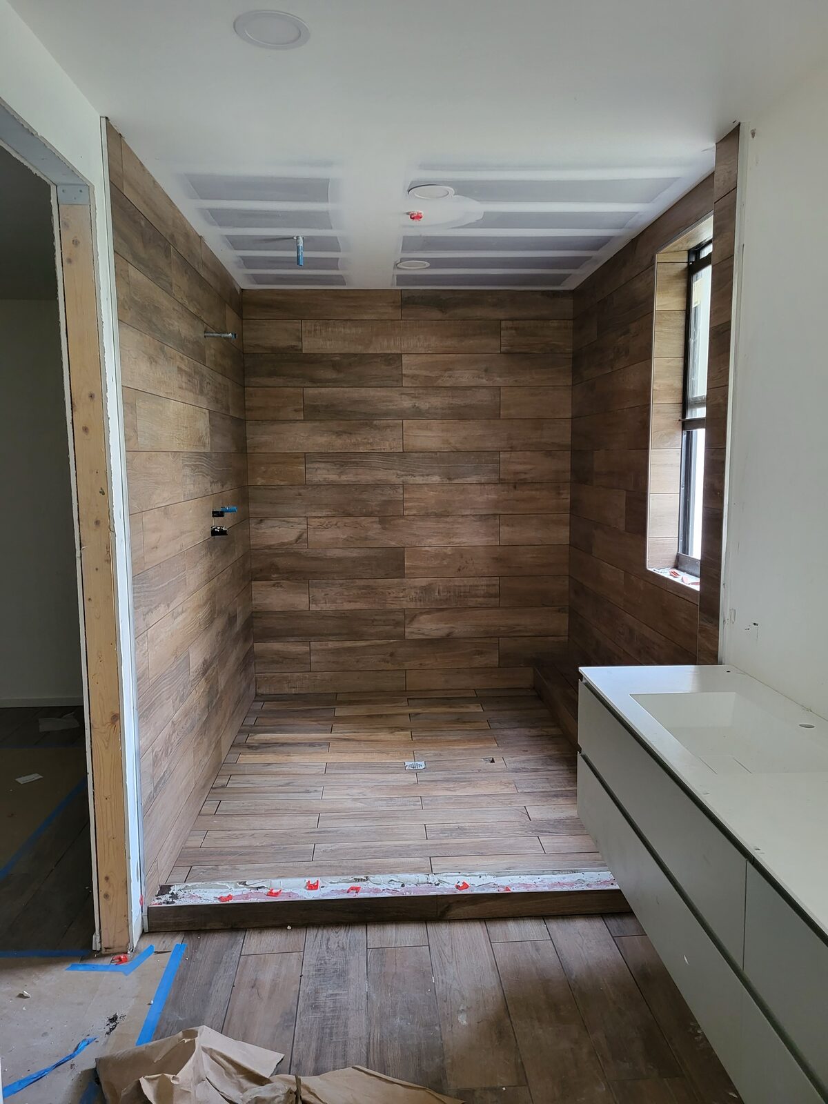 Bathroom remodel with wood-look porcelain tile throughout walls and floor