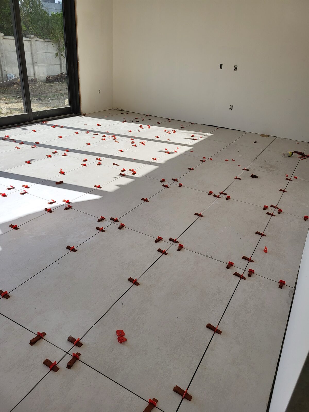 Large-format tile floor installation with leveling system in new construction home